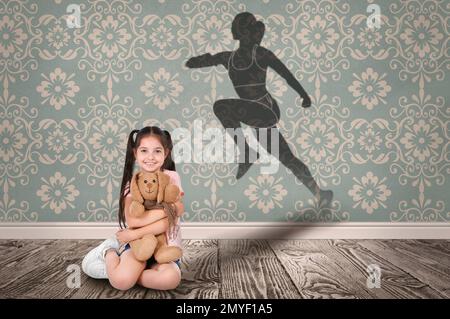 Bambina con giocattolo morbido che sogna di essere runner. Silhouette di donna dietro la schiena del bambino Foto Stock