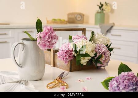 Bella ortensia fiori e forbici su tavolo bianco in cucina. Design degli interni Foto Stock