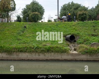 Il tubo sporge dalla pendenza. Drenaggio dell'acqua dalle acque piovane nel fiume. Industria. Sistema di drenaggio in città. Foto Stock