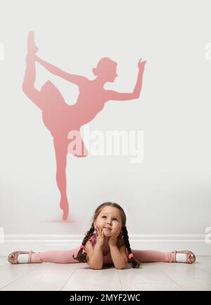 Ragazza piccola cute che sogna di essere ballerina del balletto. Silhouette di donna dietro la schiena del bambino Foto Stock