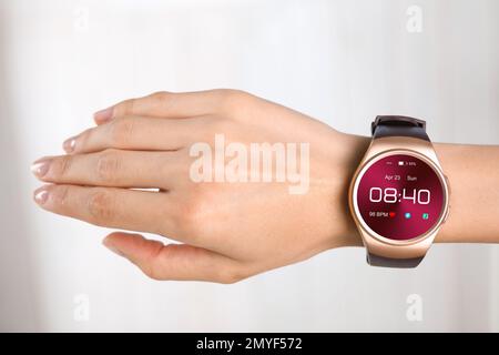 Donna con orologio intelligente che visualizza ora, data e frequenza cardiaca, primo piano Foto Stock