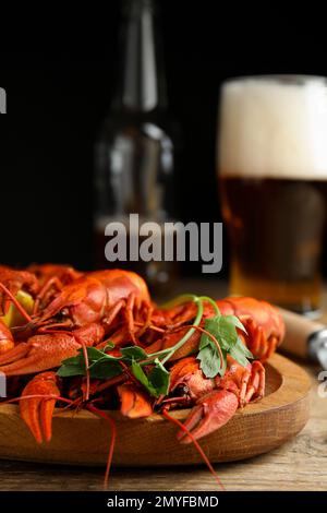 Deliziosi gamberi rossi bolliti e birra su tavolo di legno, primo piano Foto Stock