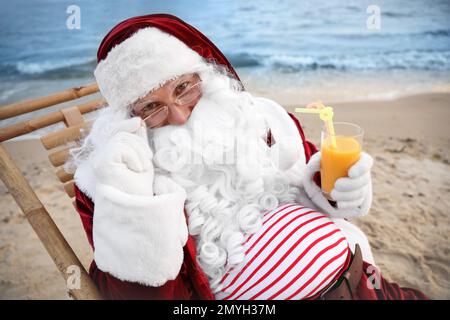 Babbo Natale con cocktail rilassante in spiaggia. Vacanze di Natale Foto Stock