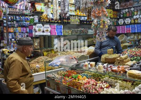 Un uomo in abiti curdi tradizionali acquistare dolci al negozio di caramelle nel souq (mercato), Duhok, Iraq settentrionale Foto Stock