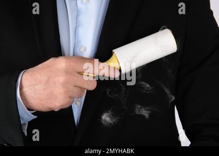 Uomo che rimuove i capelli dalla giacca nera con rullo per pelucchi, primo piano Foto Stock