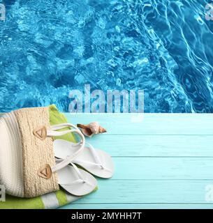 Accessori da spiaggia su ponte in legno turchese vicino alla piscina, piatto. Spazio per il testo Foto Stock