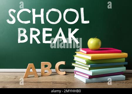 Text School Break sulla lavagna verde vicino al tavolo. Vacanze stagionali Foto Stock
