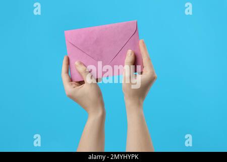 Donna con busta di carta rosa su sfondo azzurro, primo piano Foto Stock
