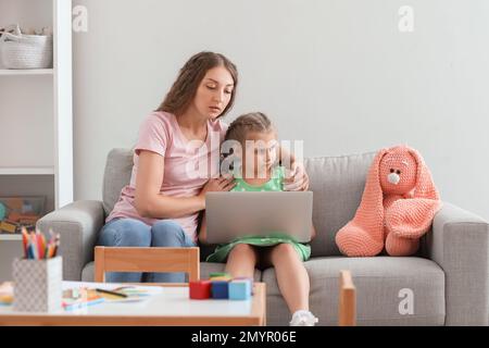 Bambina con la madre che ha sessione in linea dello psicologo nel paese Foto Stock