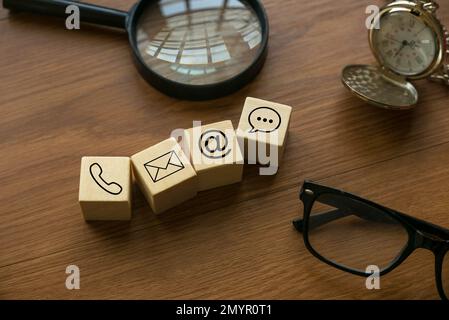 Varietà di approcci di contatto. Icona di telefono, e-mail, posta e chat su un cubo di legno. Foto Stock