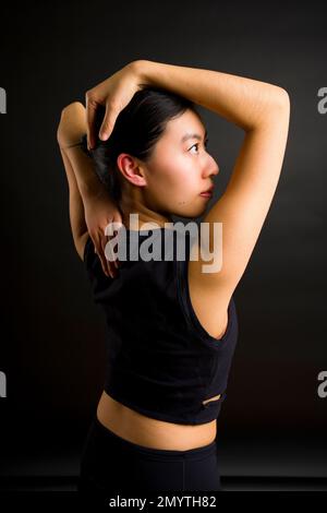 1/2 Body Back View of Young Asian Woman | Face in Profile with Arms Framing Head looking ascendente Foto Stock