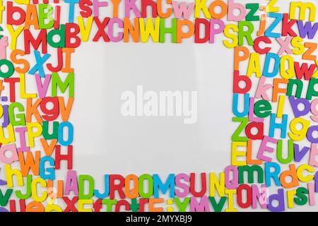 Magneti alfabetici colorati su lavagna bianca che rendono la cornice per lo spazio di copia Foto Stock