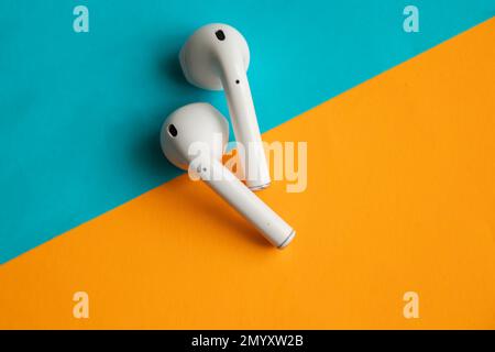 le cuffie wireless si trovano su uno sfondo colorato Foto Stock