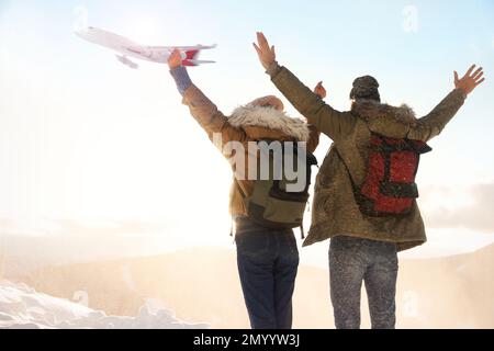 Coppia eccitata in montagna sotto il cielo con aereo volante. Vacanze invernali Foto Stock