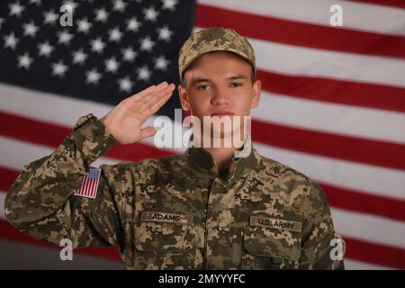 Soldato maschio che saluta contro la bandiera americana. Servizio militare Foto Stock