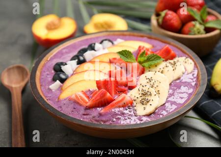 Delizioso frullato di acai con frutta fresca sul tavolo, primo piano Foto Stock