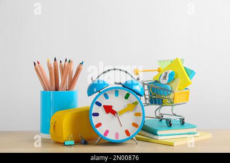 Cancelleria diversa scuola e sveglia sul tavolo su sfondo bianco. Ritorno a scuola Foto Stock