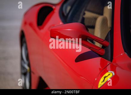 Calafat, Spagna, 18 aprile 2021: Dettaglio di uno specchio retrovisore di una Ferrari F430 rossa, parcheggiata nella zona d'attesa prima di partire per il circuito. Supercar Foto Stock
