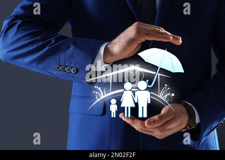 Concetto assicurativo - ombrello dimostrante protezione. Uomo con illustrazioni su sfondo scuro, primo piano Foto Stock