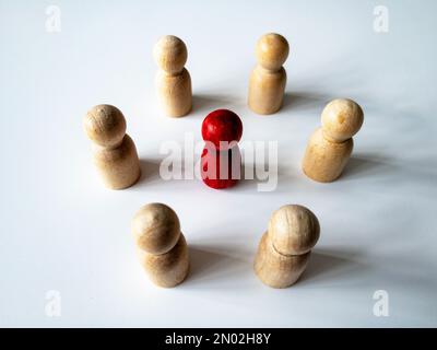 Vista laterale dall'alto della bambola rossa in legno circondata da un'altra bambola. Concetto di molestia. Foto Stock