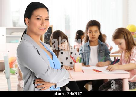 Donna asiatica felice in classe con i bambini Foto Stock