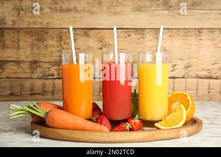 Bicchieri di deliziosi succhi di frutta e ingredienti freschi su un tavolo di legno bianco Foto Stock