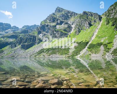 Prominente montagna rocciosa che si riflette in un lago alpino cristallino, Polonia, UE Foto Stock