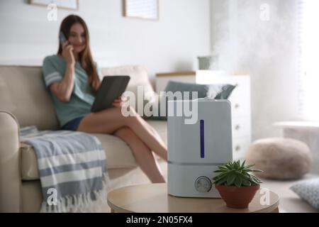 Donna con moderno umidificatore d'aria su sfondo in legno Foto stock - Alamy