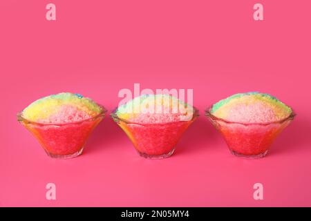 Rasatore di ghiaccio arcobaleno in ciotole di vetro da dessert su sfondo rosa Foto Stock