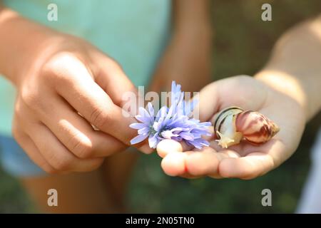 Bambini che giocano con le lumache carine all'aperto, primo piano. I bambini trascorrono del tempo in natura Foto Stock