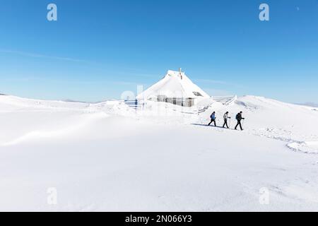Splendido paesaggio dopo forti nevicate sull'alpeggio velika Planina, fiabesco paesaggio invernale, alberi innevati, escursionisti che passano da cottage tradizionali Foto Stock