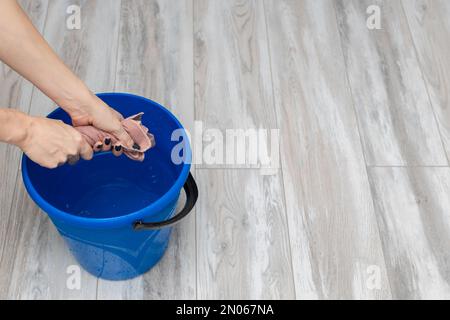 donna che strizzava fuori uno straccio bagnato durante la pulizia. uomo che pulisce la stanza. pulizia del pavimento bagnato Foto Stock