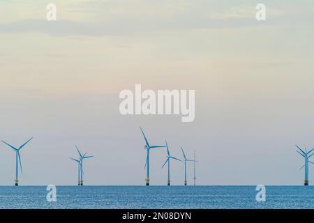 Turbine eoliche all'orizzonte nel mare, parte della Kentish Flats Wind Offshore Farm al largo della costa del Kent a Herne Bay. Cielo blu. Spazio di copia. Foto Stock