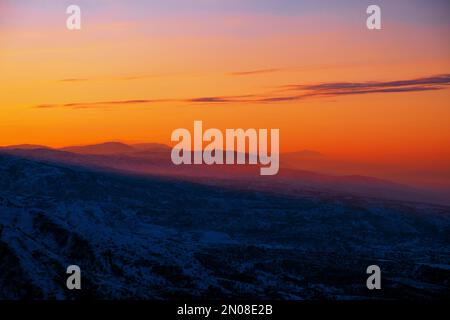 Atmosfera magica di un tramonto nelle Highlands; cielo del tramonto su creste di montagna innevate Foto Stock