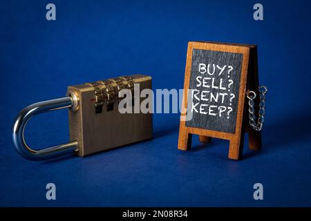 Acquisto Vendita conservazione in affitto. Lavagna e lucchetto in miniatura su sfondo blu. Foto Stock