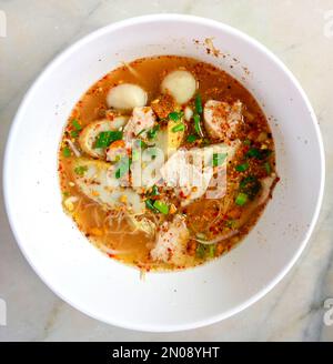 Tom Yum Noodles in stile thailandese con zuppa piccante di maiale tritata con bacchette di legno Foto Stock