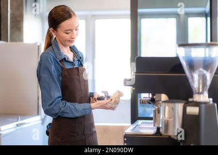 la signora della caffetteria sta preparando le attrezzature per l'apertura del negozio per servire le bevande del caffè ai clienti con servizio standard, pulizia e int Foto Stock