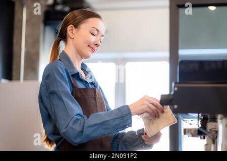 la signora della caffetteria sta preparando le attrezzature per l'apertura del negozio per servire le bevande del caffè ai clienti con servizio standard, pulizia e int Foto Stock