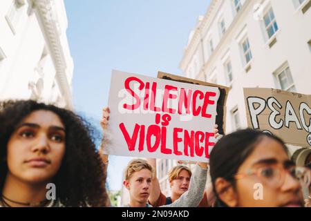 Diversi giovani si oppongono alla guerra e alla violenza. Attivisti giovanili multiculturali che protestano con manifesti e striscioni. Gruppo di adolescenti campa Foto Stock