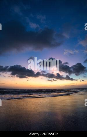 Uno scatto verticale di una bella riva di un mare calmo al tramonto Foto Stock