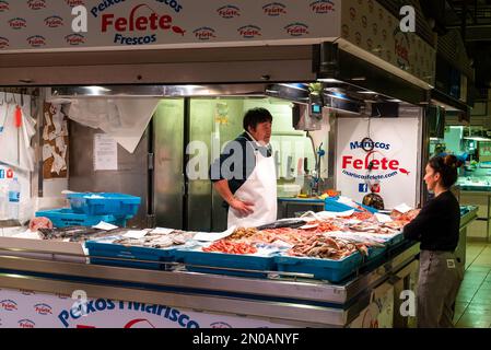 Alicante, Spagna - 2 febbraio, 2023: Pescivendolo parla con il cliente nel vecchio mercato interno di Alicante Foto Stock