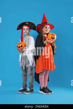 Carino bambini piccoli con secchi caramelle zucca indossare costumi di Halloween su sfondo blu Foto Stock