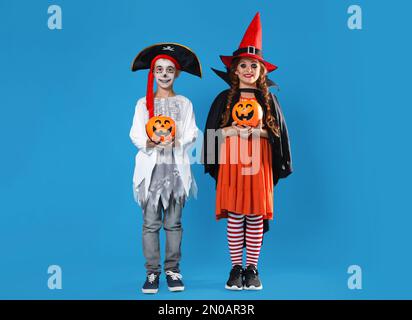 Carino bambini piccoli con secchi caramelle zucca indossare costumi di Halloween su sfondo blu Foto Stock