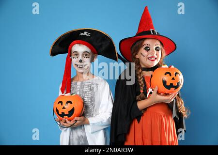 Carino bambini piccoli con secchi caramelle zucca indossare costumi di Halloween su sfondo blu Foto Stock