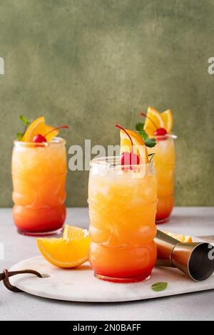Punch al rum in bicchieri tiki guarnito con fette di arancia e ciliegia con spazio copia Foto Stock
