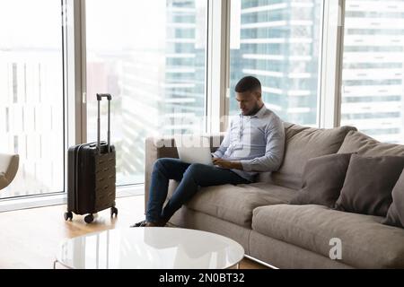 Un giovane professionista concentrato che lavora sul computer portatile in viaggio di lavoro Foto Stock