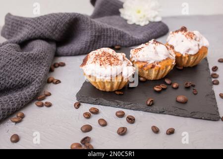 3 cupcakes fatti in casa su una piastrella di pietra nera, fuoco morbido primo piano Foto Stock