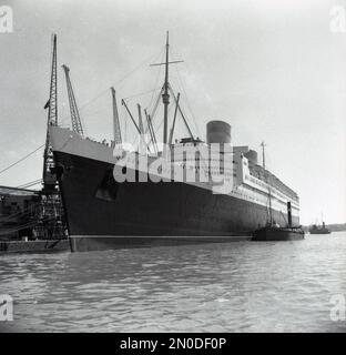 1950s, storica, RMS Queen Elizabeth ormeggiata nei moli di Southampton, Hampshire, Inghilterra, Regno Unito. Gestito dalla Cunard Line, il lussuoso transatlantico navigava settimanalmente da Southampton, Inghilterra, Regno Unito a New York, USA, via Cherbourg in Francia. Costruita nel 1930s da John Brown & Co sulla Clyde in Scozia, fu nominata in onore della Regina Elisabetta, in seguito Regina Madre. Quando fu lanciata nel 1938, fu la più grande nave passeggeri mai costruita, rimanendo così fino al 1994. Foto Stock