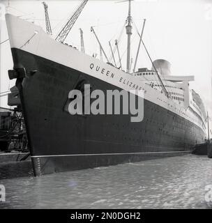 1950s, storica, RMS Queen Elizabeth ormeggiata nei moli di Southampton, Hampshire, Inghilterra, Regno Unito. Gestito dalla Cunard Line, il lussuoso transatlantico navigava settimanalmente da Southampton, Inghilterra, Regno Unito a New York, USA, via Cherbourg in Francia. Costruita nel 1930s da John Brown & Co sulla Clyde in Scozia, fu nominata in onore della Regina Elisabetta, in seguito Regina Madre. Quando fu lanciata nel 1938, fu la più grande nave passeggeri mai costruita, rimanendo così fino al 1994. Foto Stock