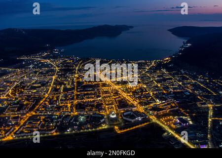 Vista notturna di Magadan da un'altezza. Grande città nell'Estremo Oriente della Russia. Il centro amministrativo della regione del Magadan. Molti edifici e bello Foto Stock